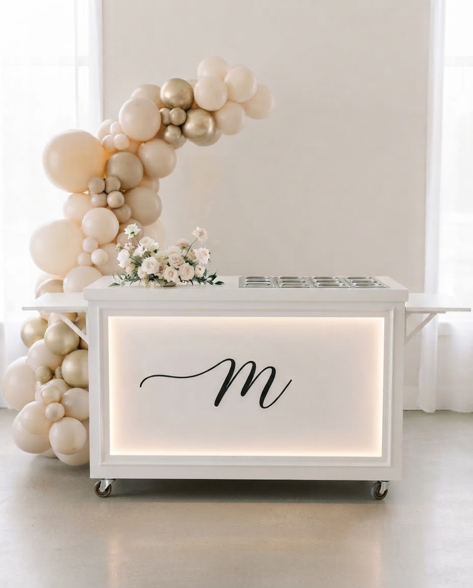 White mobile event cart with a custom monogram decal on the backlit front panel at an Edmonton wedding